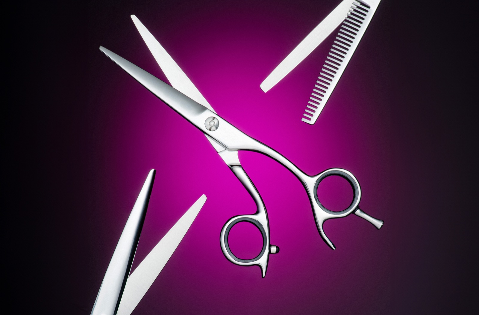 Polished hairdressing scissors photographed against a rich plum background